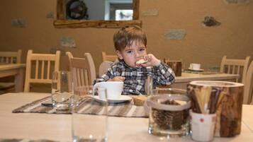 Un enfant est assis à une table devant une tasse, un verre et un bocal rempli de graines.