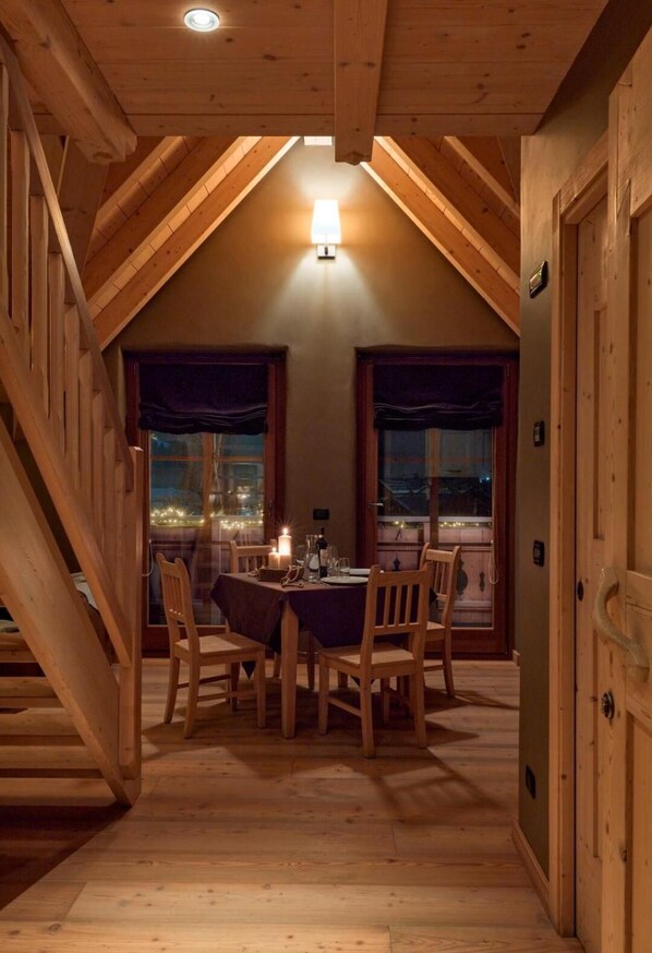 A cozy dining area with a table set for four, wooden chairs, and a chandelier.