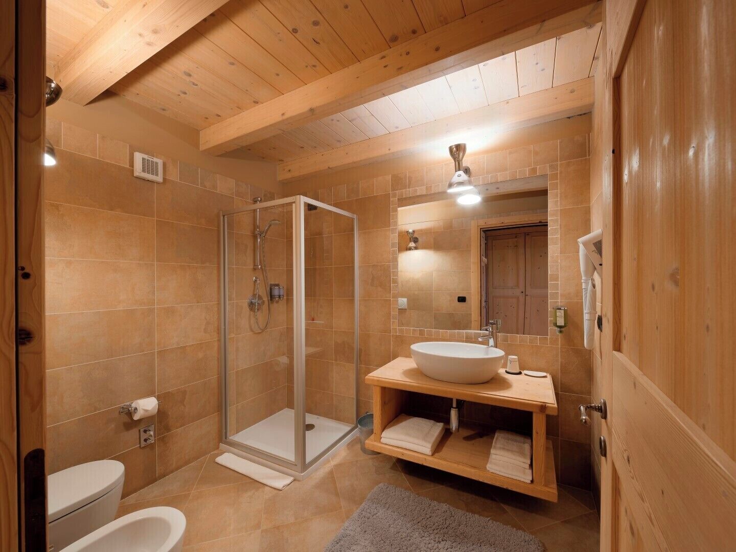 Ein Badezimmer mit Holzausstattung, einer Glasdusche, einem weißen Waschbecken und einer Toilette.