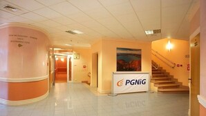 A hotel lobby with a curved reception desk, a staircase, and a banner with the PGG logo. - Centrum Konferencyjno-Rekreacyjne Czarna (Czarna)
