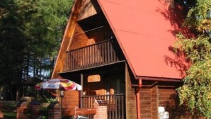 A rustic cabin with a red roof, wooden walls, and a porch with a bench. - Centrum Konferencyjno-Rekreacyjne Czarna (Czarna)