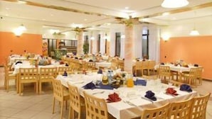 A dining area with multiple round tables covered with white tablecloths, wooden chairs, and various dining items. - Centrum Konferencyjno-Rekreacyjne Czarna (Czarna)