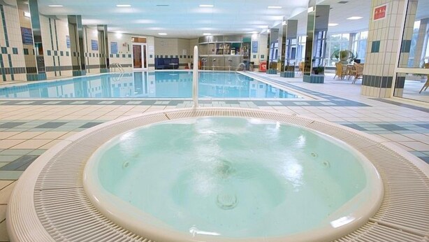 An indoor swimming pool with a hot tub in the center, surrounded by tiled walls and a seating area with tables and chairs. - Centrum Konferencyjno-Rekreacyjne Czarna (Czarna)