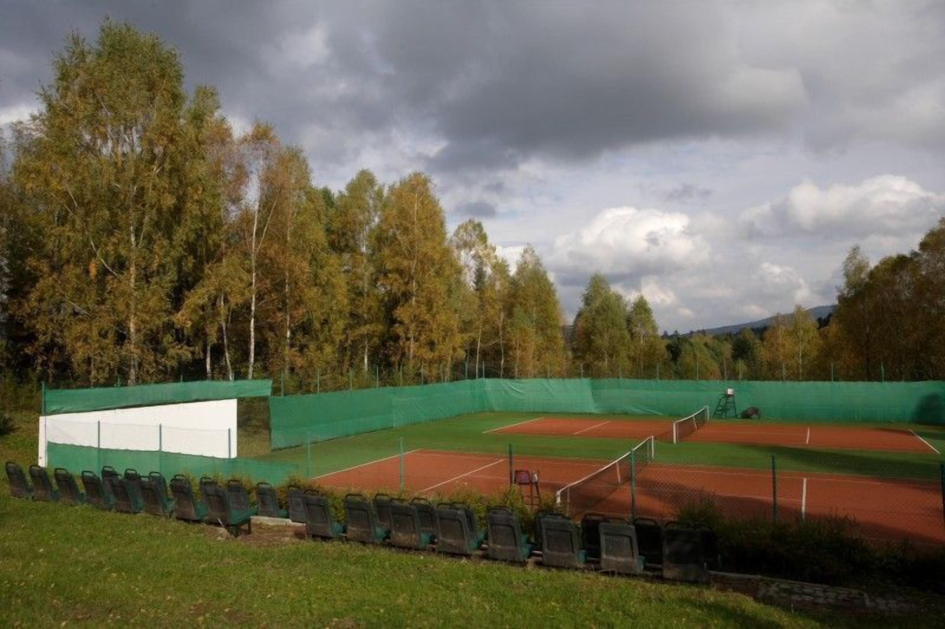 Un court de tennis en plein air avec un filet vert et des sièges.