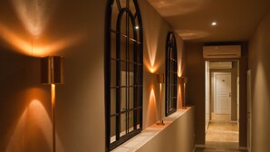 A hallway with arched windows, recessed lighting, and a door at the end. - Black 5 Florence (Florence)