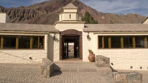 A building with a central entrance, large windows, and a mountainous backdrop. - Marques de Tojo Hotel (Purmamarca)