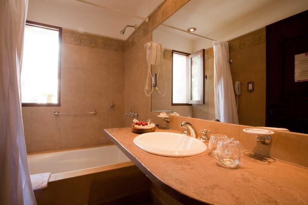 A bathroom with a bathtub, a sink, a hairdryer, and a mirror.