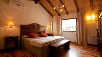 A bedroom with a wooden ceiling, a bed with pillows, a nightstand, a bench, and a window with curtains.