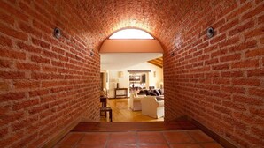 A brick-walled hallway leading to a living area with a sofa and a coffee table. - Marques de Tojo Hotel (Purmamarca)