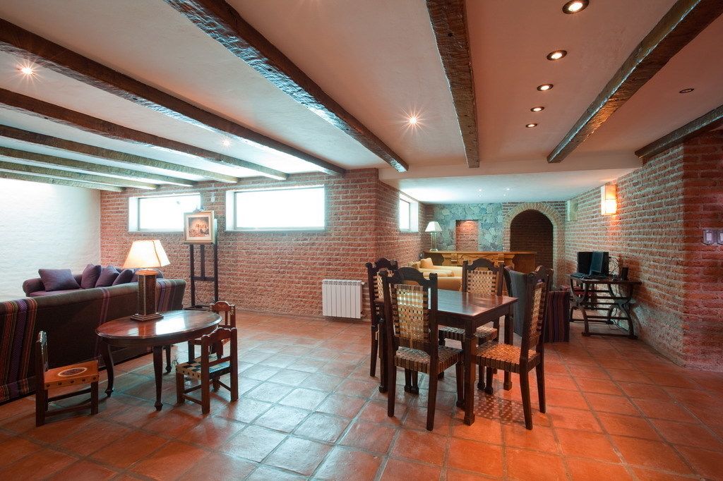 Un amplio salón con pared de ladrillo, chimenea y una mesa de comedor con sillas.