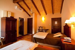 Habitación de hotel con dos camas, muebles de madera, una araña y una lámpara de pared.