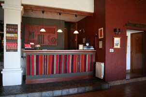 Uma área de recepção com balcão, luminárias pendentes e uma parede vermelha.