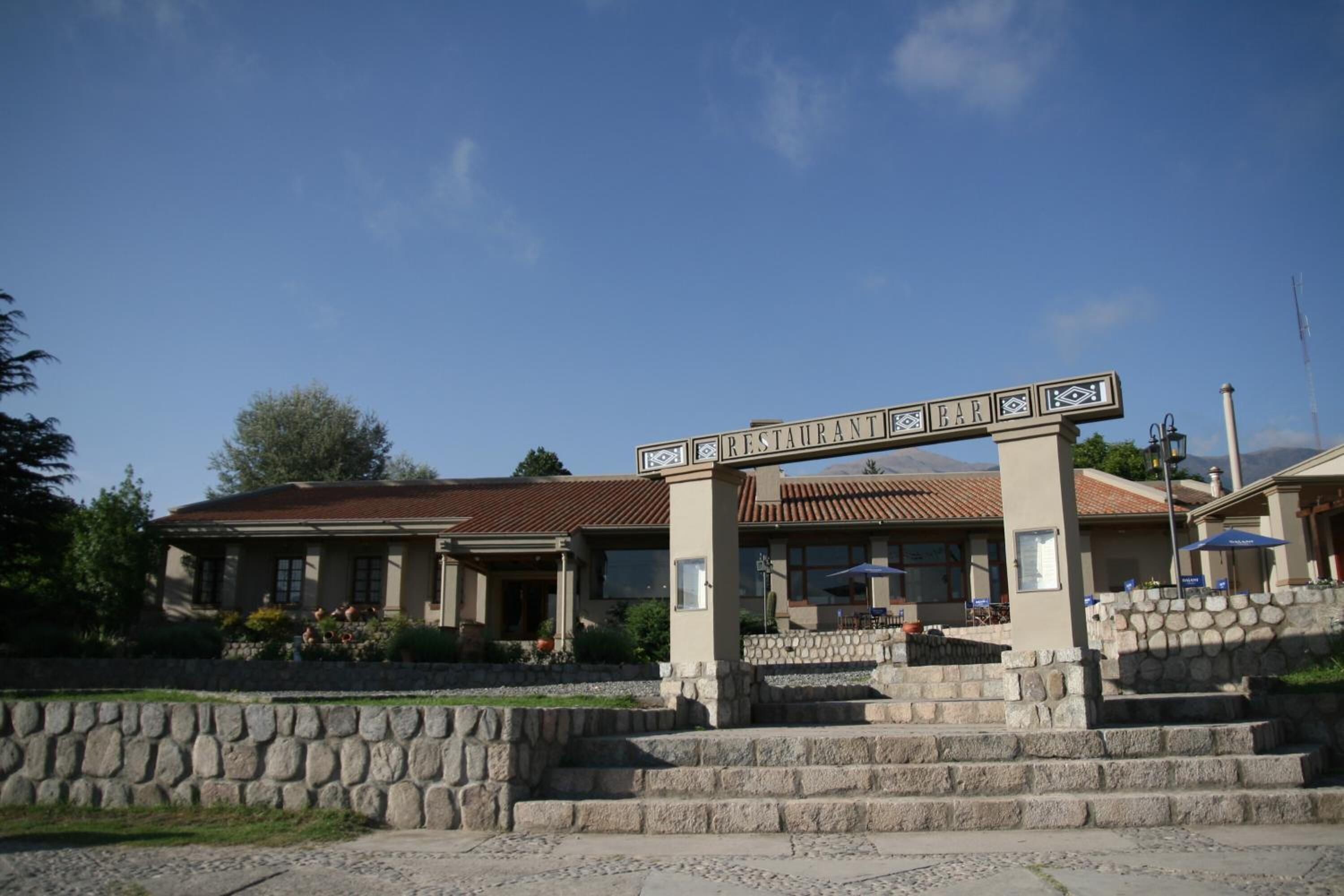 Un restaurant avec une façade en pierre, un toit recouvert de tuiles et une enseigne au-dessus de l’entrée.
