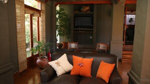 Uma sala de estar aconchegante com um sofá de couro, duas poltronas, uma TV e uma lareira.