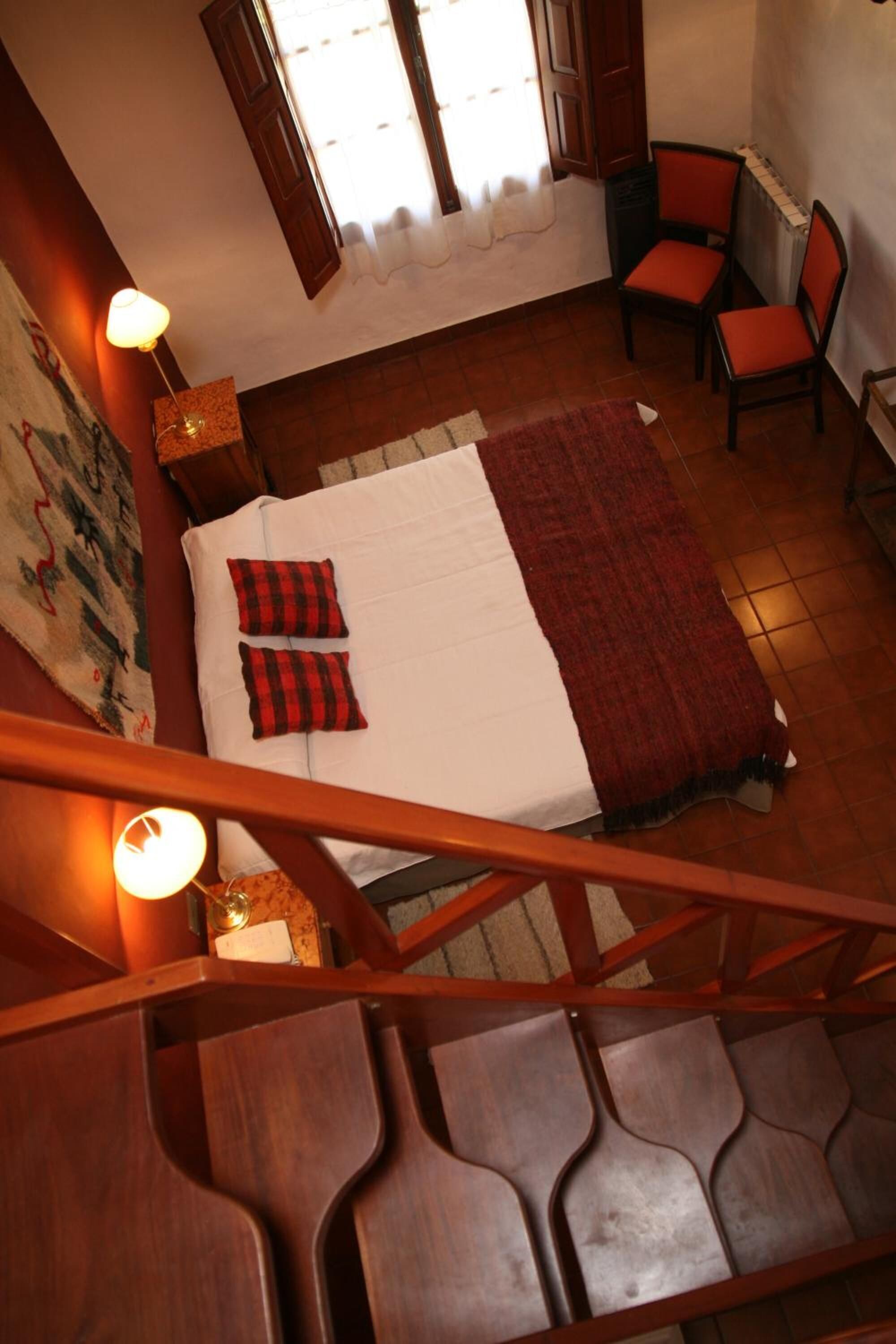 Un dormitorio con cama, dos sillas, una ventana y una escalera.
