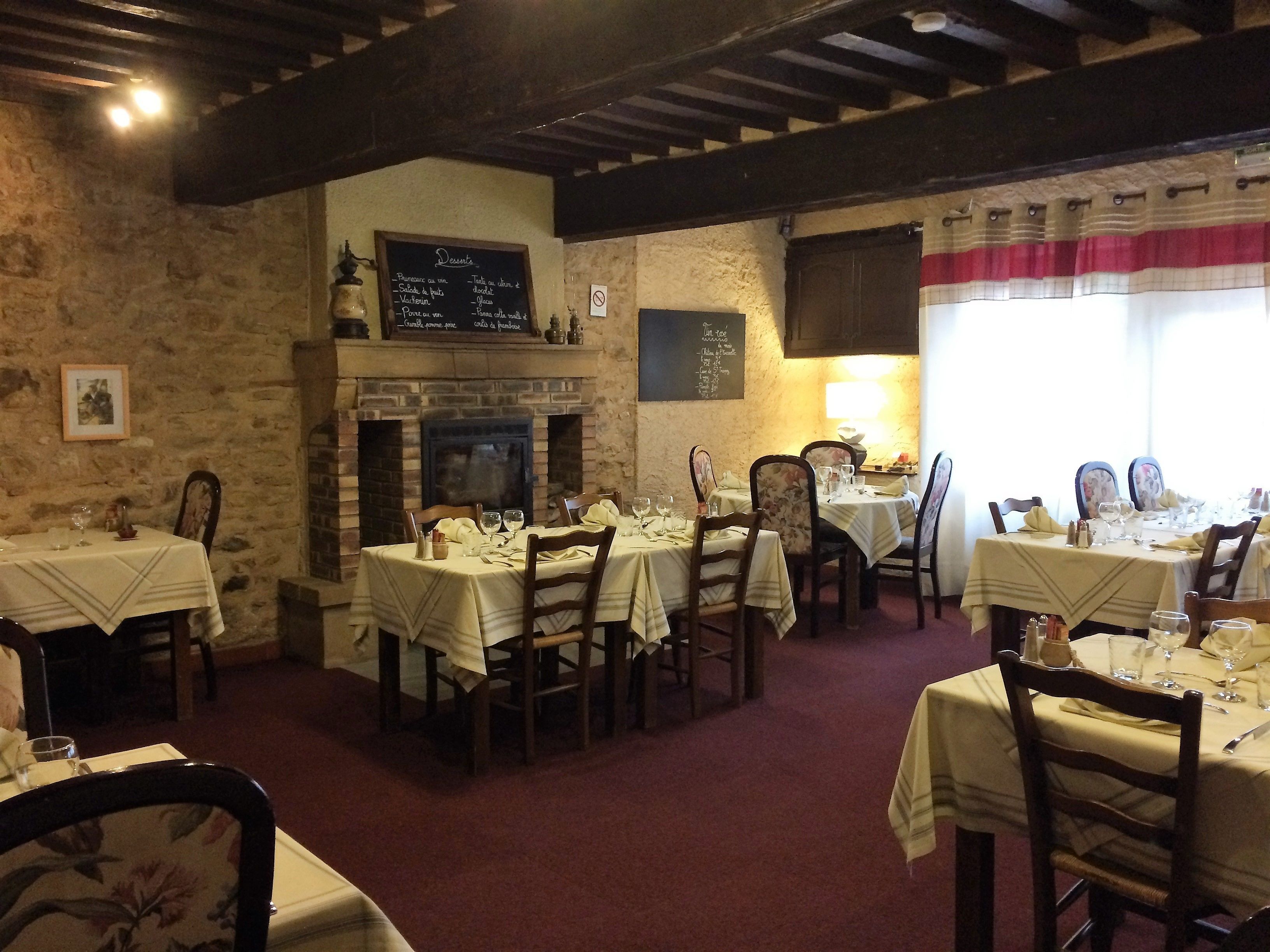 Un restaurante con paredes de piedra, vigas de madera y mesas dispuestas para comer.