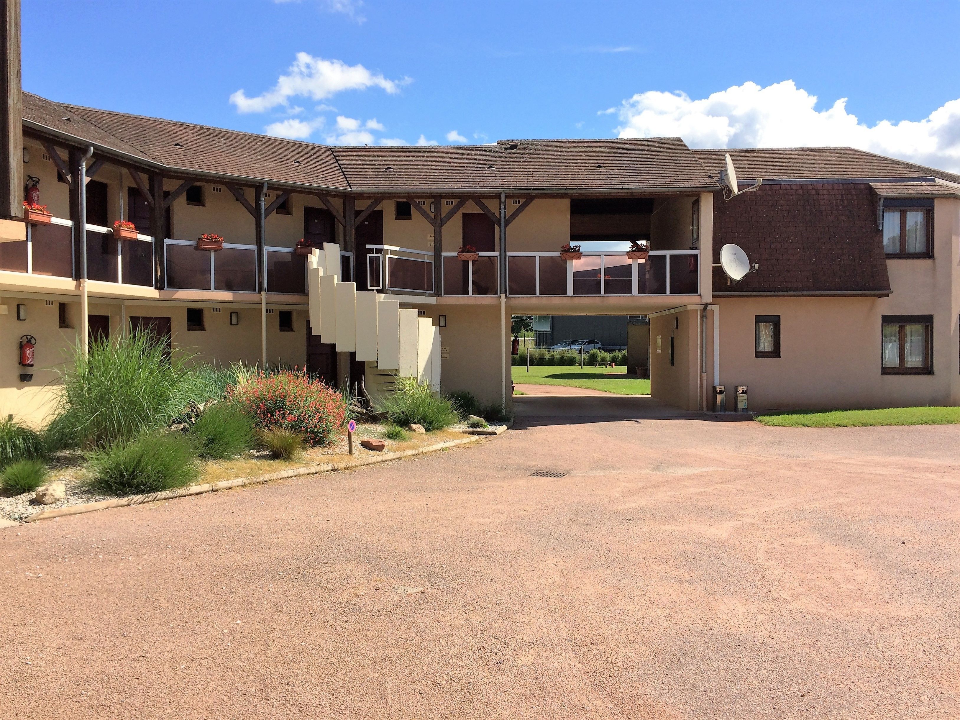 A multi-story building with a covered outdoor area, a gravel driveway, and a satellite dish.