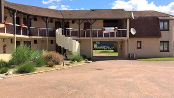 A multi-story building with a covered outdoor area, a gravel driveway, and a satellite dish.