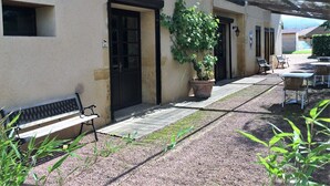 A building with a covered patio area, a bench, and a potted plant. - Delfotel (Hautefond)