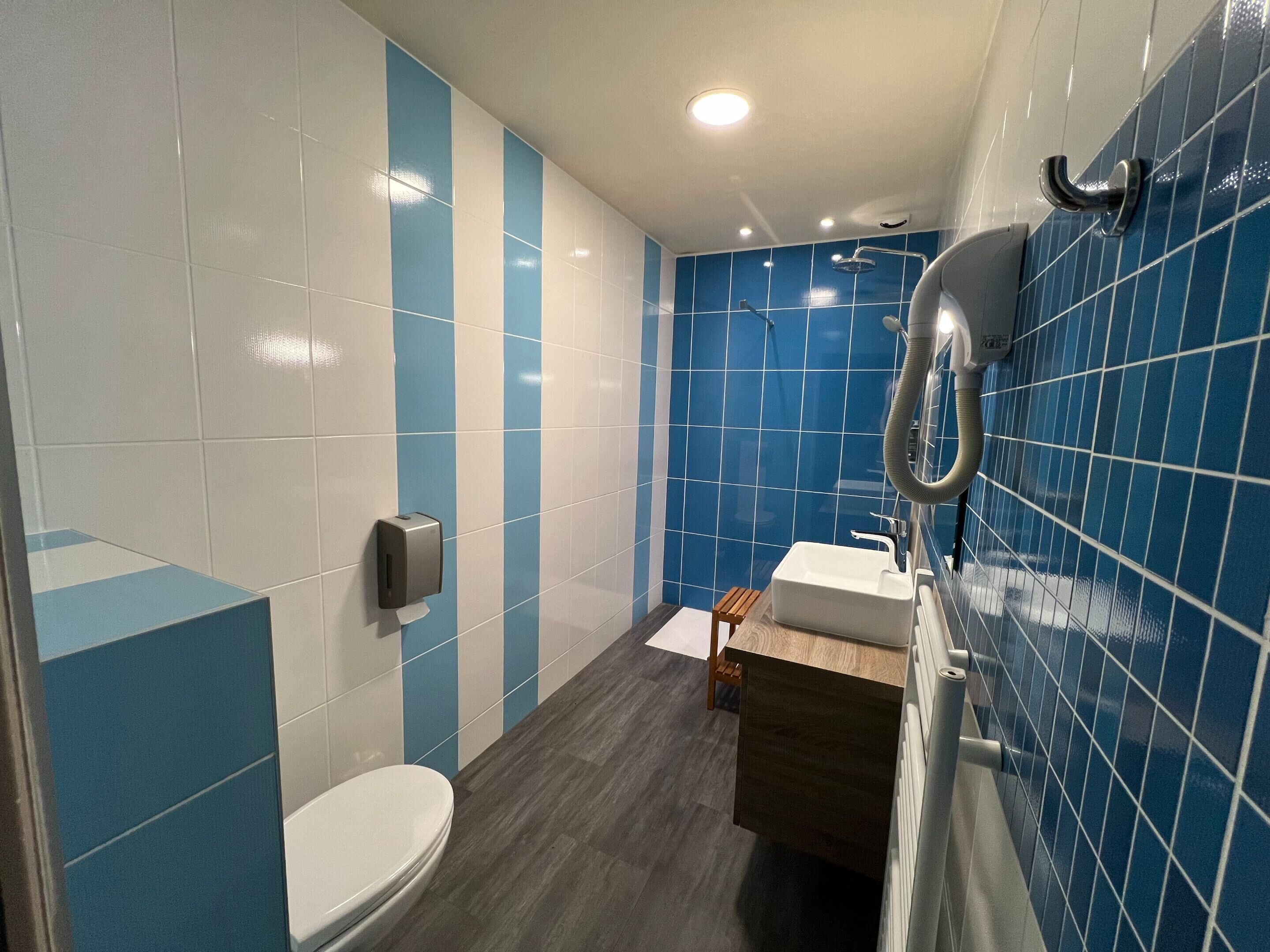 Une salle de bain moderne équipée de toilettes, d’un lavabo et d’une douche.