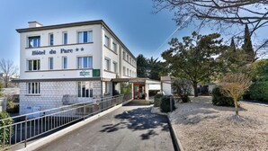 A hotel named "Hotel du Parc" with a modern facade, a covered entrance, and a pathway leading to the entrance.