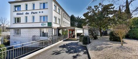 A hotel named "Hotel du Parc" with a modern facade, a covered entrance, and a pathway leading to the entrance.