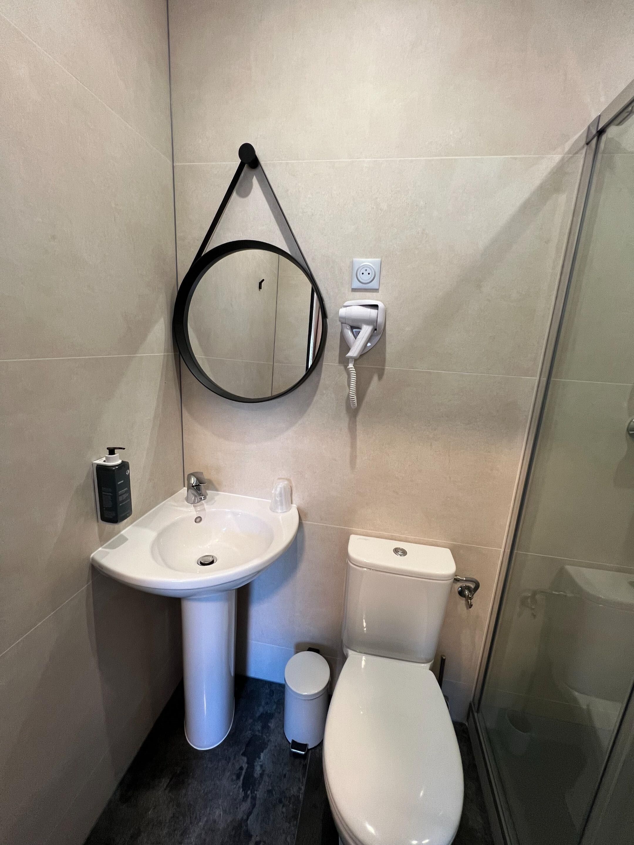 A bathroom with a sink, mirror, toilet, and a glass shower enclosure.