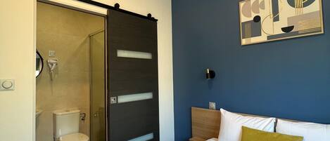 A hotel room with a bed, a bathroom, and a shower.