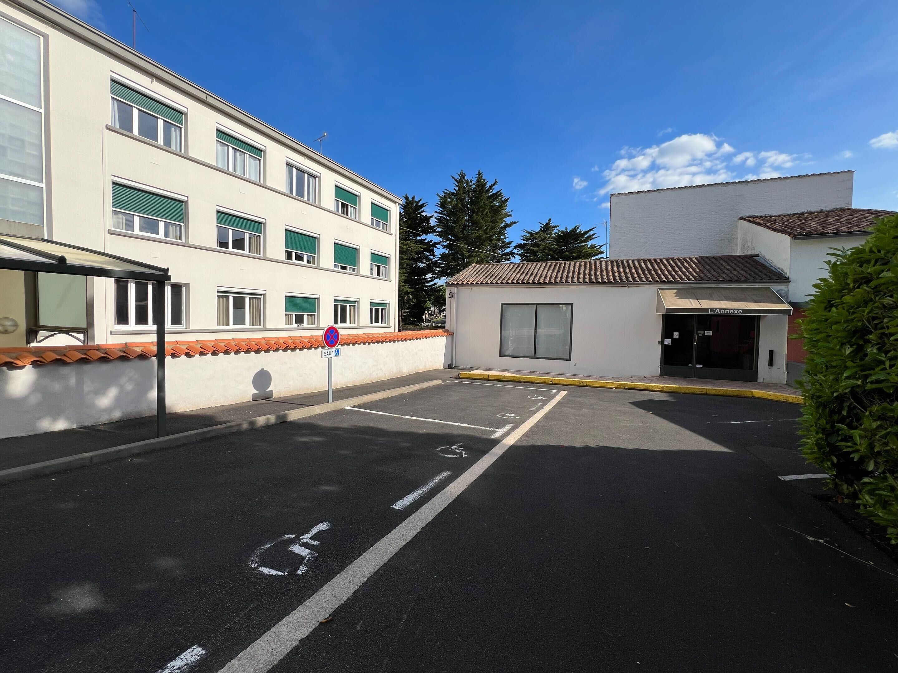 A parking area with a handicapped parking space, a bus stop shelter, and a building with a sign reading "L'Annexe".