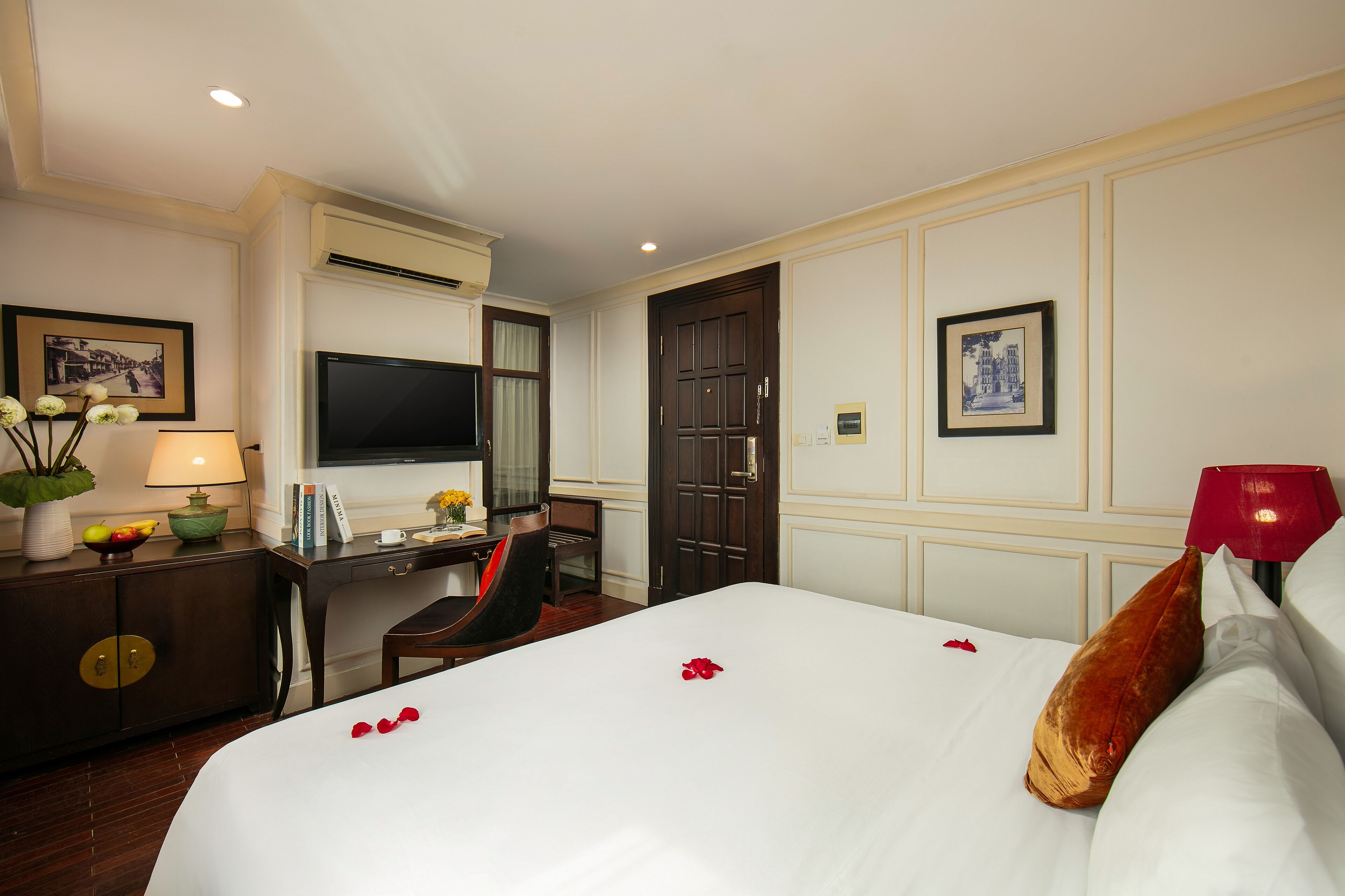 Een hotelkamer met een groot bed, een bureau met stoel, een televisie en een deur.