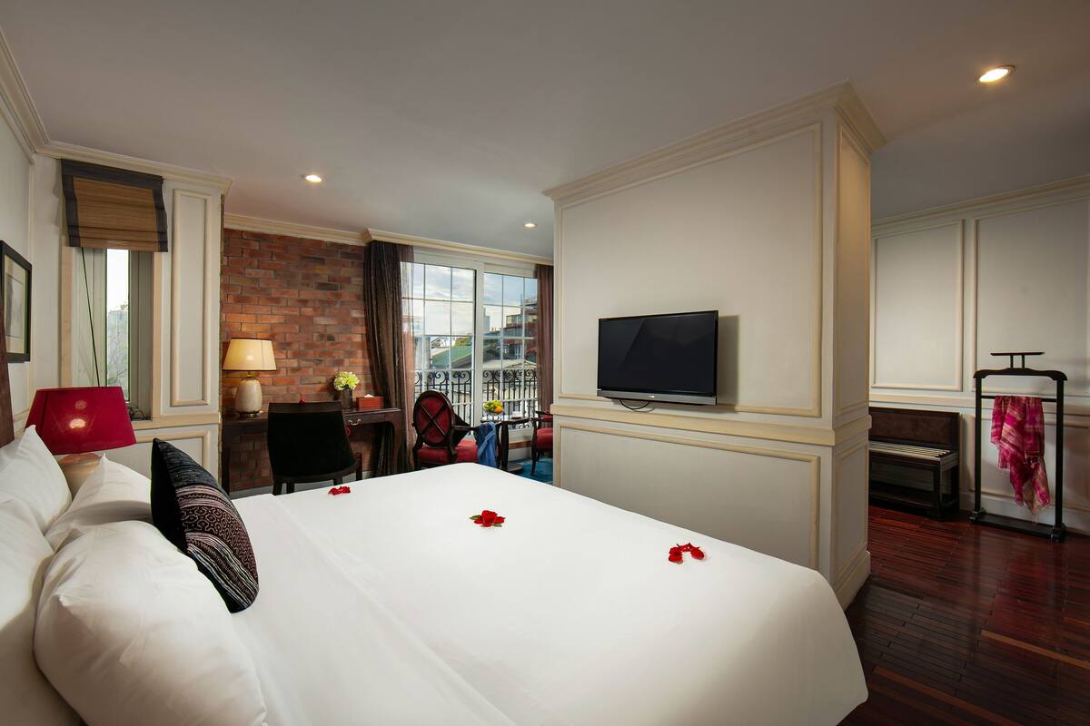 Habitación de hotel con una cama grande, televisión, escritorio con silla y vista a la ciudad desde la ventana.
