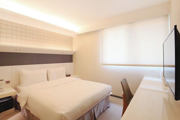A hotel room with a bed, bedside table, and a flat-screen TV.