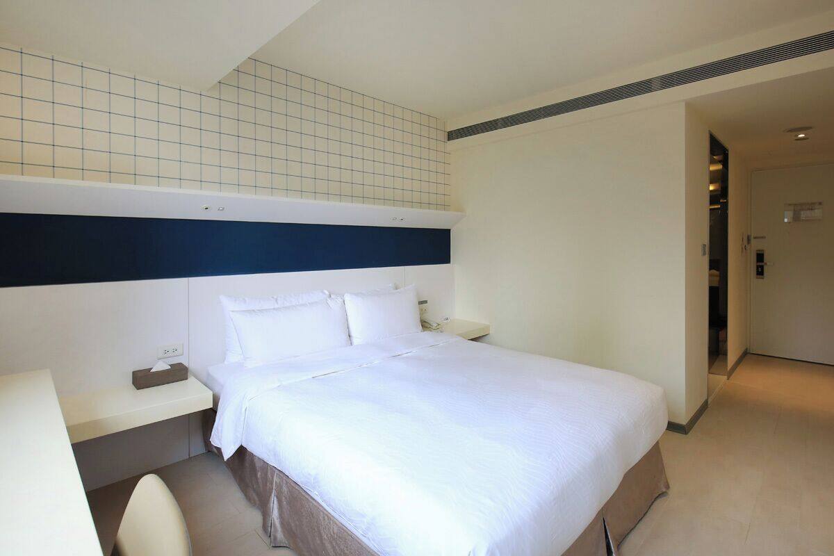 A hotel room with a large bed, bedside tables, a desk, and a chair.