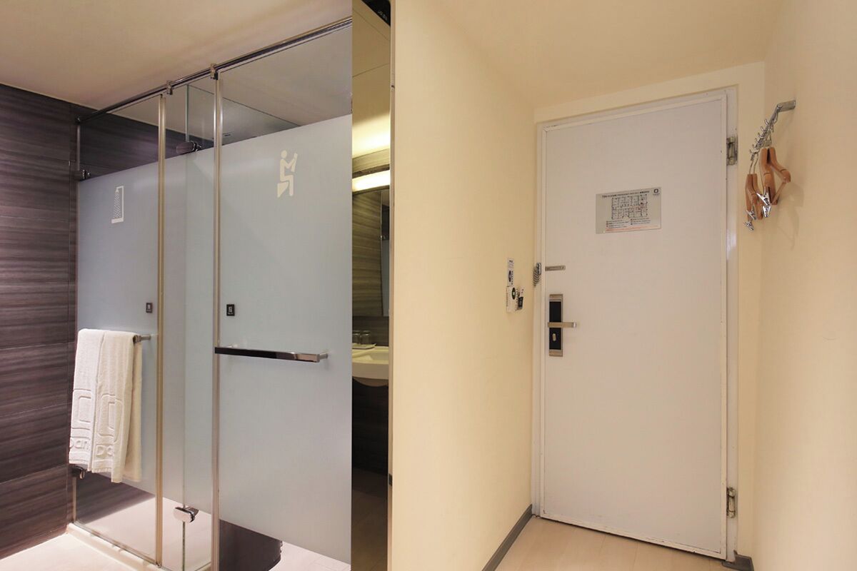 A hotel room with a glass partition, a white door, and a towel rack.
