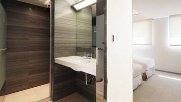 A modern bathroom with a dark wood vanity, a white sink, and a glass shower enclosure.