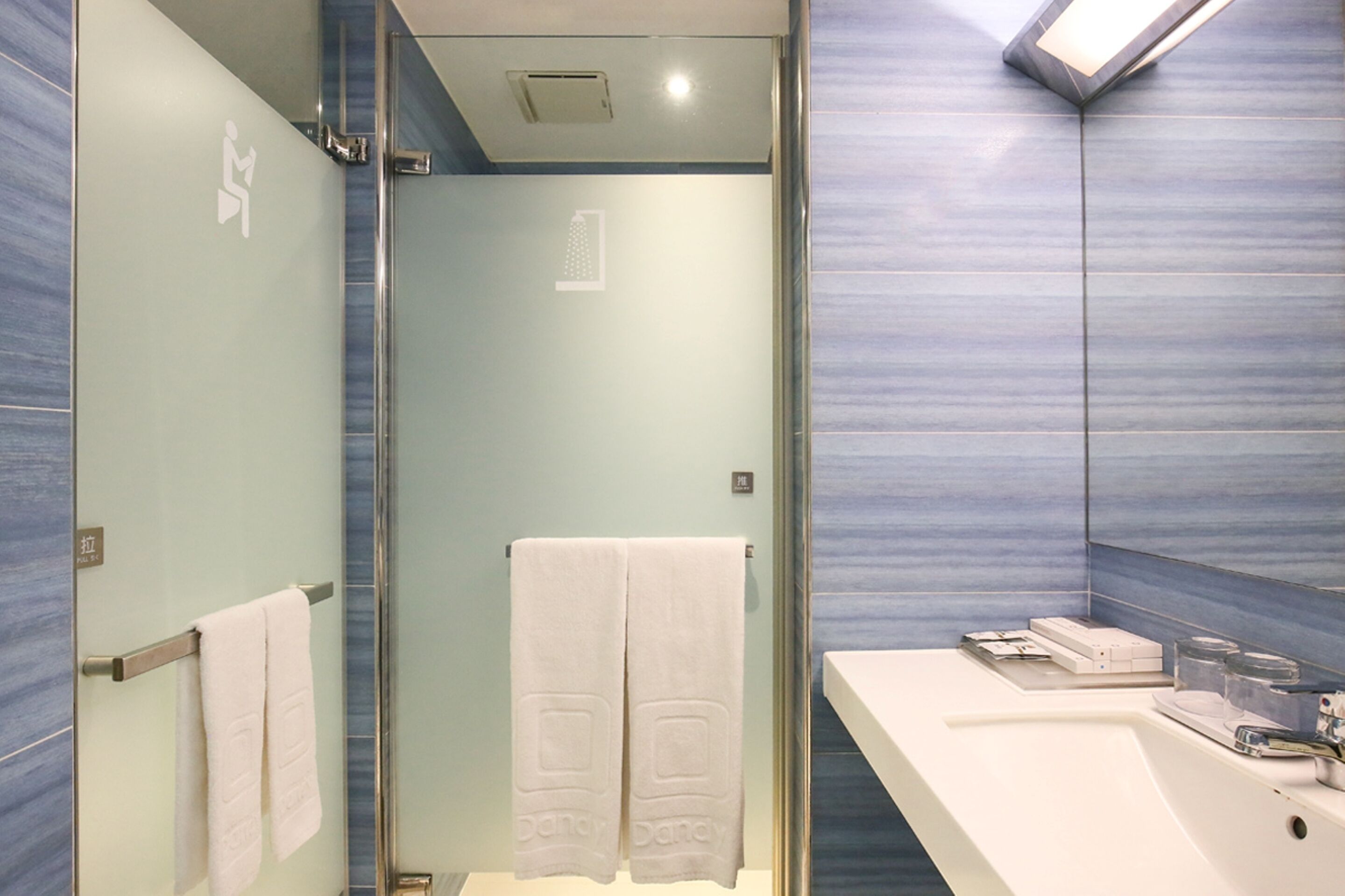 Un baño moderno con cabina de ducha de vidrio, un lavabo blanco y un perchero para toallas.