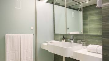 A modern bathroom with a large mirror, white sink, and glass shower enclosure.