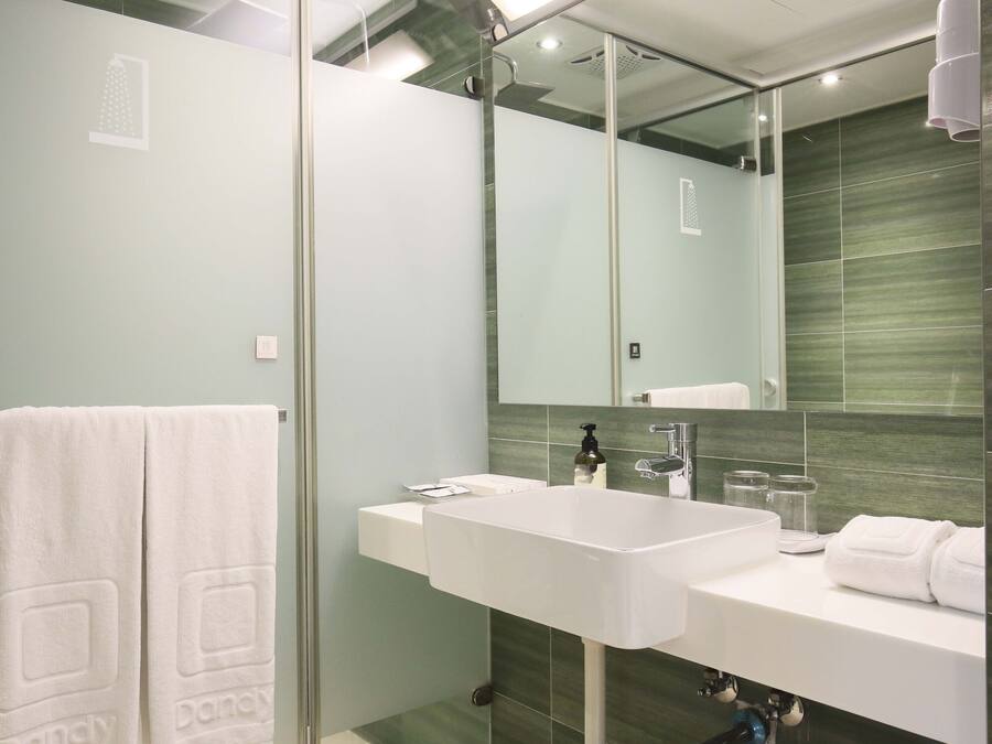 A modern bathroom with a large mirror, white sink, and glass shower enclosure.
