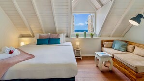 Une chambre avec un grand lit, un canapé, une petite table et une fenêtre donnant sur un beau paysage.