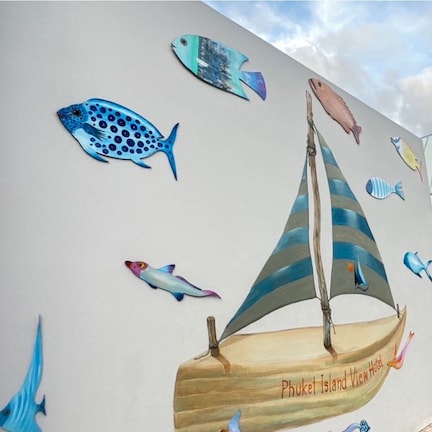 A mural of a sailboat with various fish and a lighthouse on a wall.