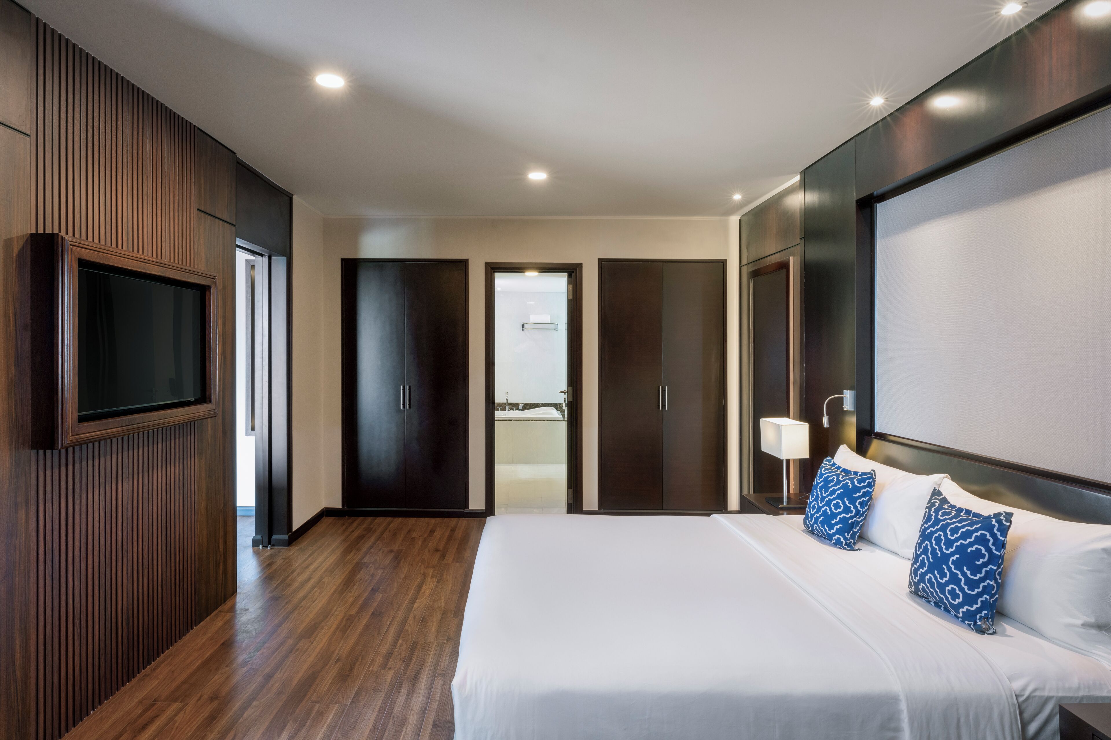 Une chambre d’hôtel moderne dotée d’un grand lit, de lambris en bois, d’un téléviseur à écran plat et donnant sur le balcon.