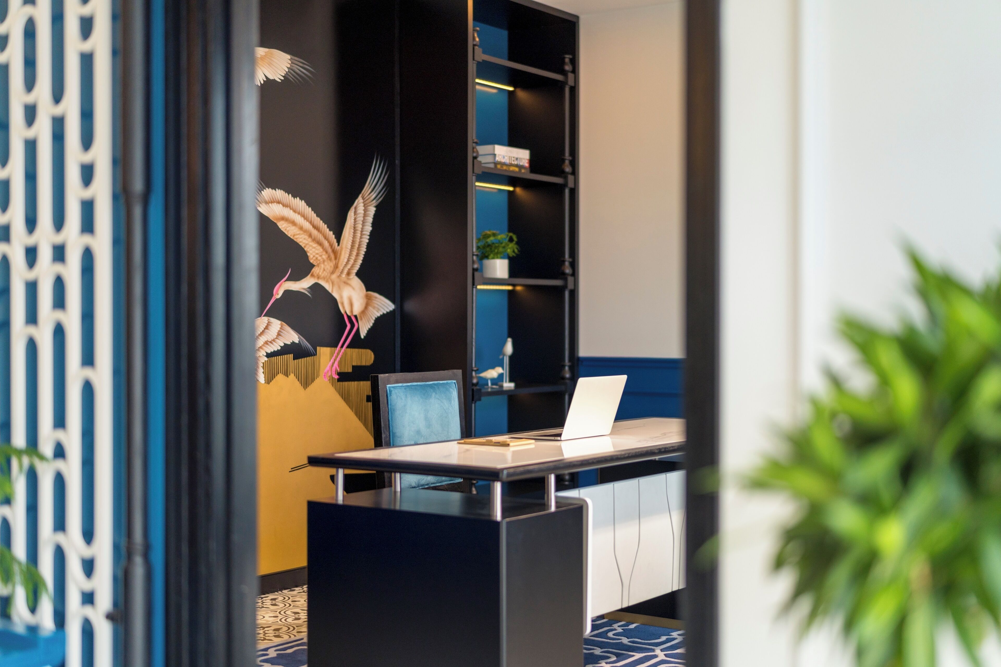A modern office space with a desk, laptop, and a bookshelf.