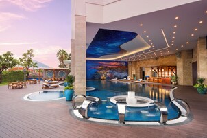 Una piscina al aire libre, sombrillas, sillones reclinables de piscina