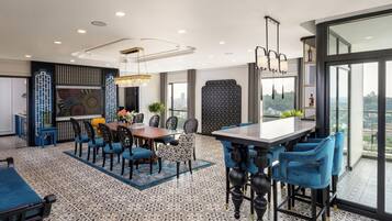 A modern dining area with a large table, blue upholstered chairs, and patterned flooring.