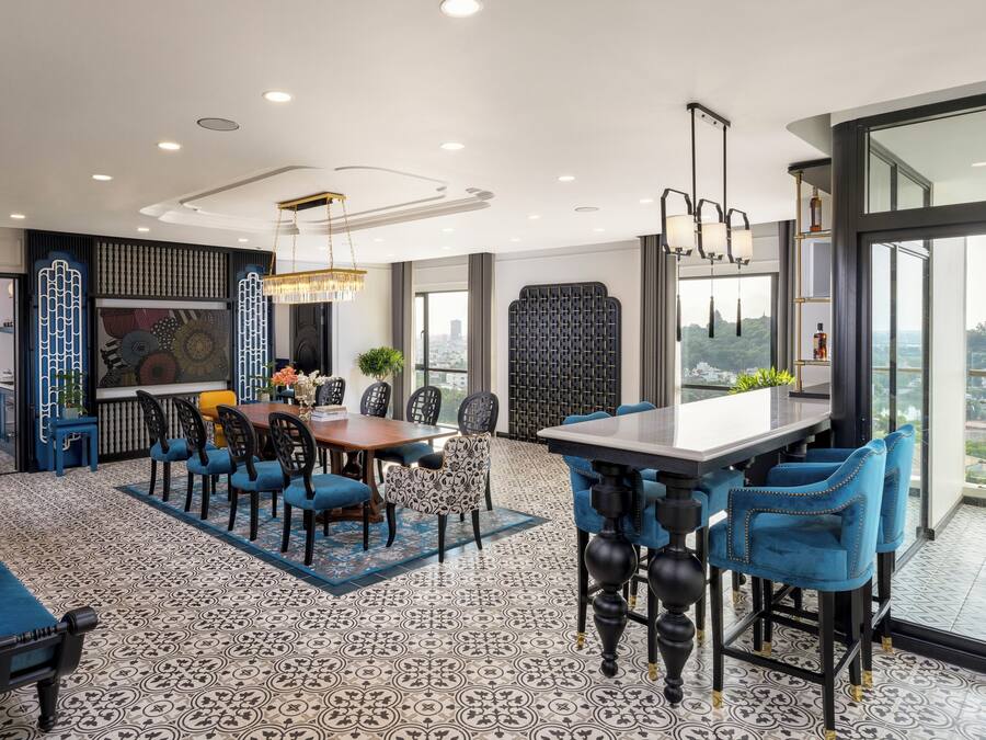 A modern dining area with a large table, blue upholstered chairs, and patterned flooring.