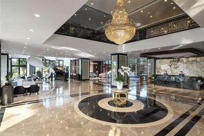 Welcome to our hotel lobby, featuring a grand chandelier, comfortable seating area, and a reception desk.