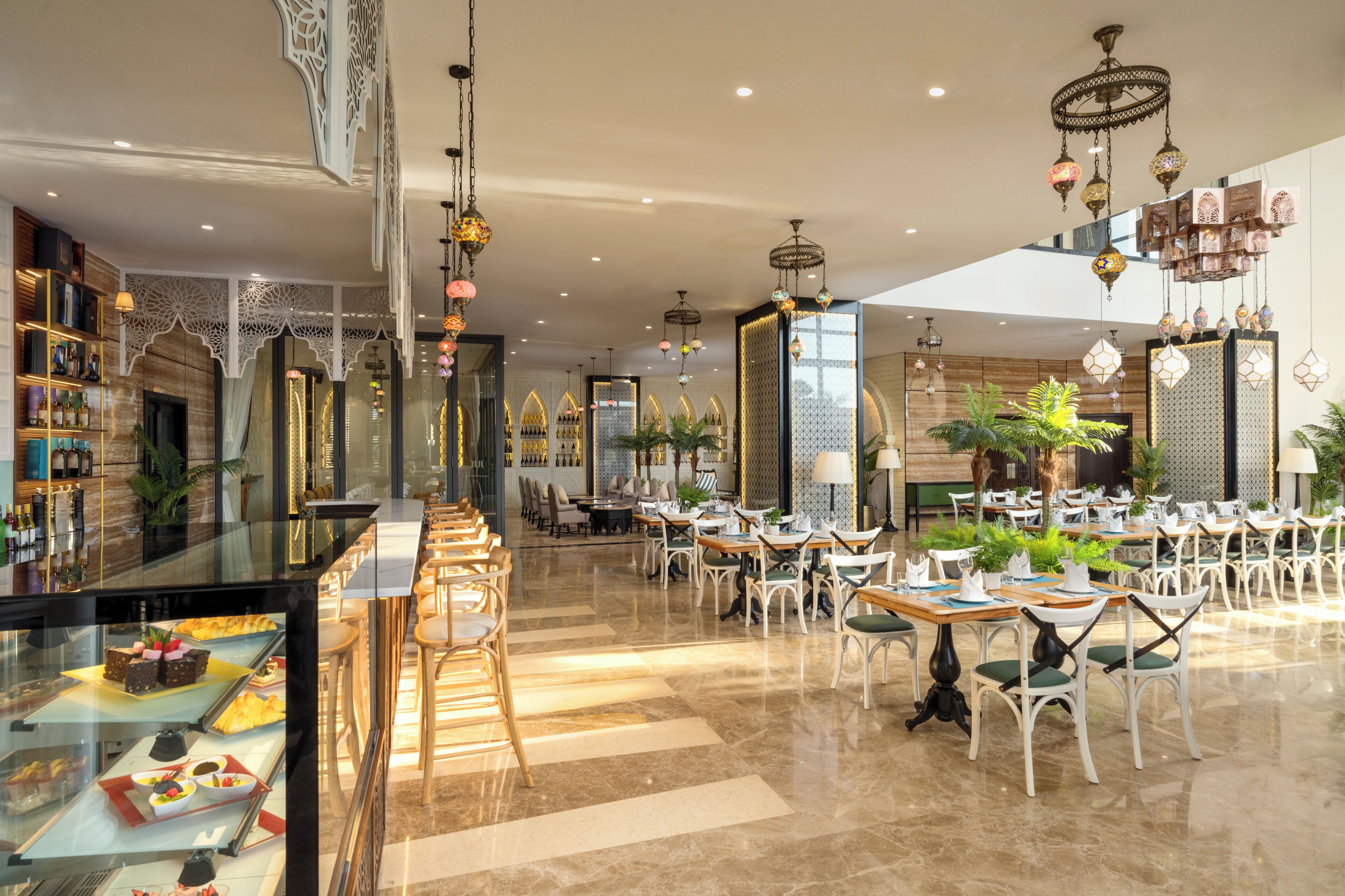 A spacious restaurant with high ceilings, chandeliers, and a variety of seating arrangements.