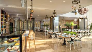 A spacious restaurant with high ceilings, chandeliers, and a variety of seating arrangements.