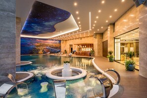 Una piscina al aire libre, sombrillas, sillones reclinables de piscina