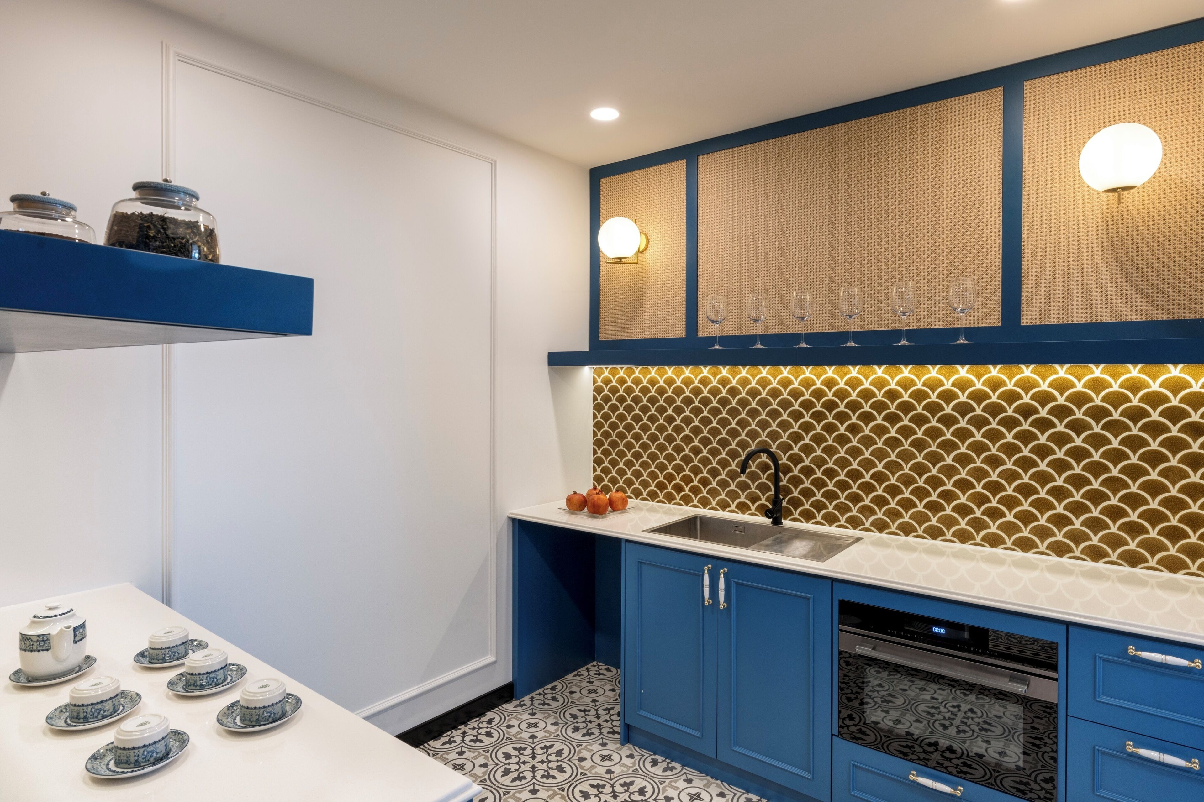 A modern kitchen with blue cabinets, a white countertop, and a patterned backsplash.